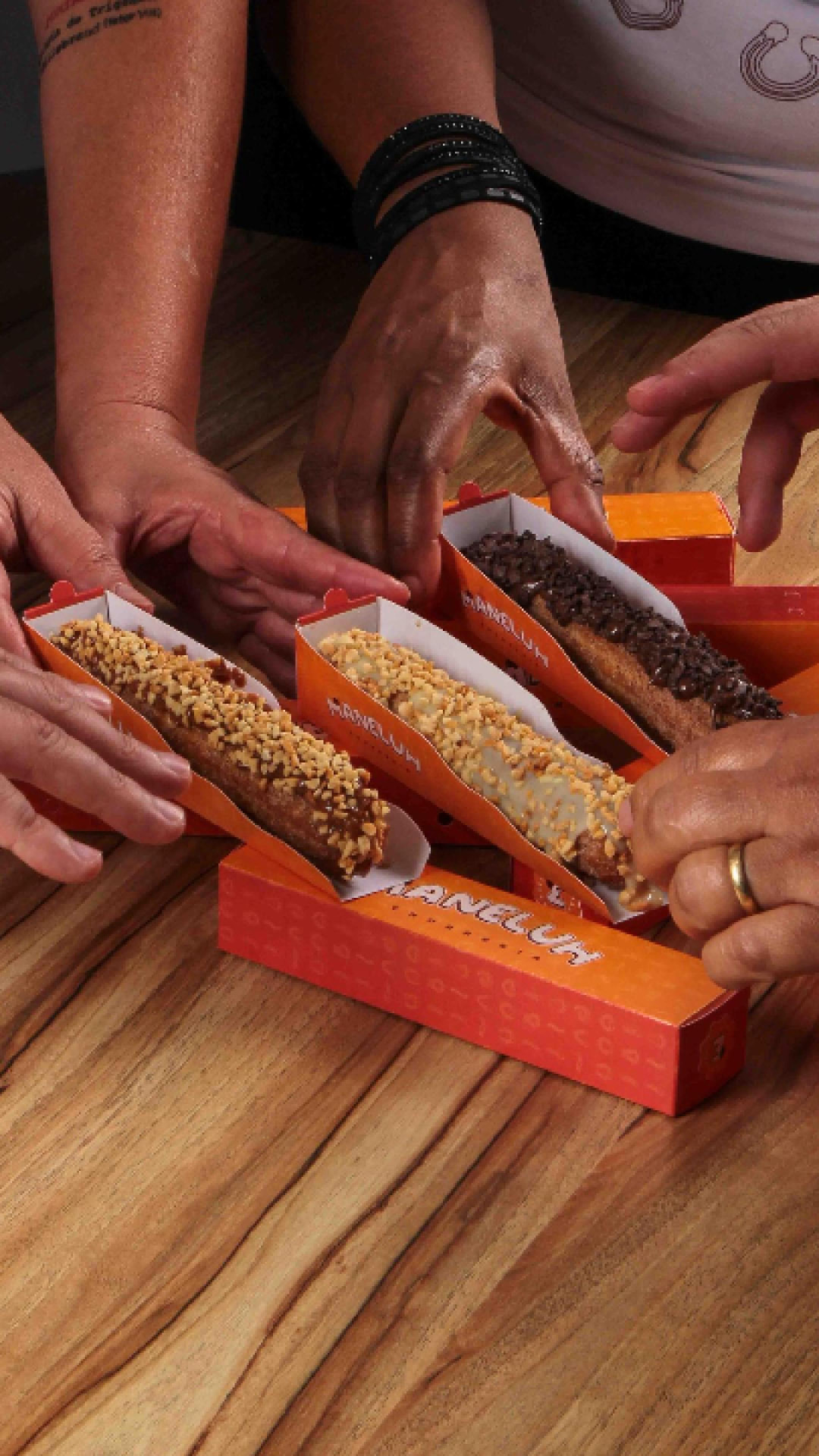 Convidados pegando churros com coberturas em caixas da Maneluh